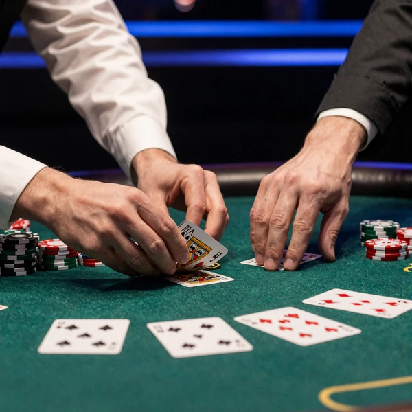 Croupier-H&auml;nde teilen Karten auf gr&uuml;nem Filz mit blauer Akzentbeleuchtung im Casea Live Casino